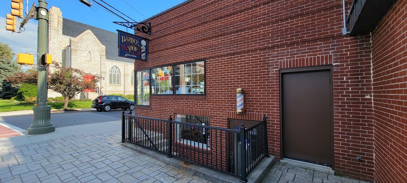 Railed stairway down to the shop, with a barber pole on the brick wall